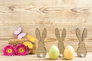 Drei Osterhasen und zwei Ostereier mit Blumen und Schmetterlingen