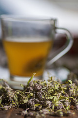 Herbal vitamin herbal tea with thyme in a transparent glass mug on a wooden table