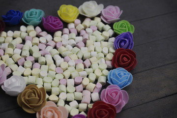 sweet marshmallows in heart shape decorated with flowers on wood background. valentine day concept.