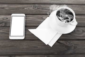 a cup of coffee, paper napkins, a smartphone on a wooden background. lunch break. breakfast.