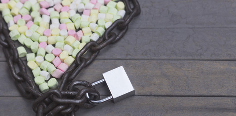 Chain and lock arranged with marshmallow for Valentine Day in heart shape on wood