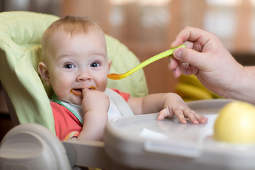 father feeding baby with spoon