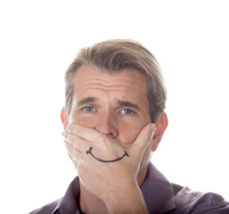 Man hiding his true emotions by covering his mouth with a fake smile drawn on his hand.