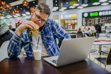 man works on laptop in cafe and it in same time