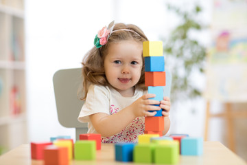 child little girl playing wooden toys at home or kindergarten