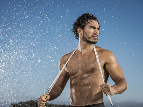 Water splashing on man holding jump rope