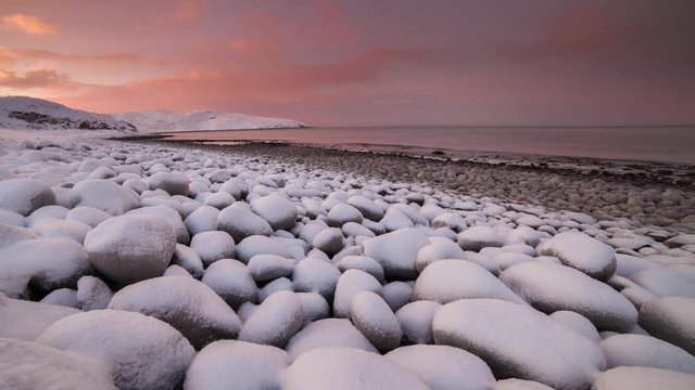 Sunset on the snow-covered beach of the Barents Sea