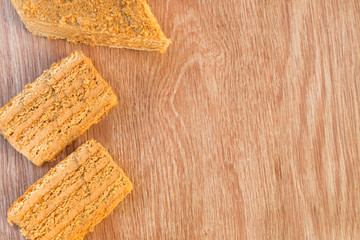 Pieces of traditional Russian baked honey cake on left of wooden table. Space for text