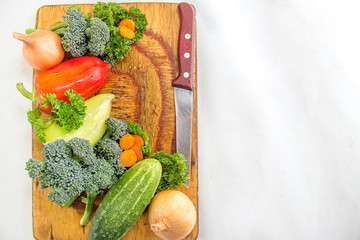 Fresh vegetables on the cutting board and knife : . yellow and red pepper, slices of carrot and broccoli sprouts, onions, cucumber. Food simple background with copyspace