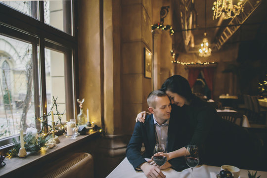 Caucasian couple drinking wine and hugging in restaurant