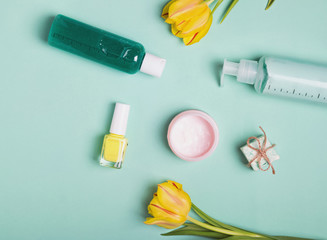 Bottles with feminine body care producs and yellow tulips on the bright background