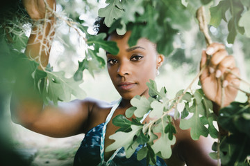 Portrait of serious mixed race woman holding tree branches