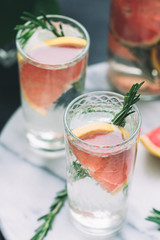 Cold detox cocktails with grapefruit and rosemary on a white marble serving tray.