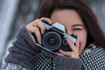 Girl looking through the old film camera in the winter park