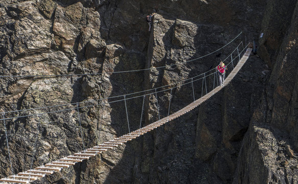 Mature Man Crossing Rope Bridge On Mountain