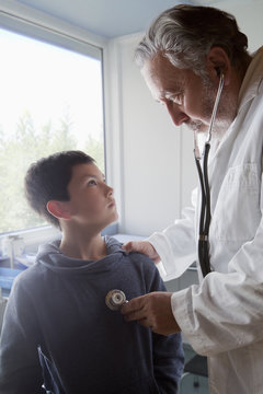 Hispanic doctor listening to chest of boy with stethoscope