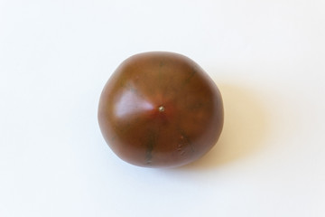 Blossom end view of a deep red green Cherokee Purple organic heirloom tomato food ingredient, isolated on white, horizontal aspect