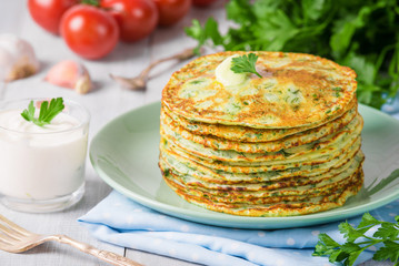 Many pancakes with fresh herbs and sour cream sauce on a wooden table. Traditional Ukrainian or Russian pancakes. Traditional dishes on the holiday Carnival Maslenitsa Shrovetide