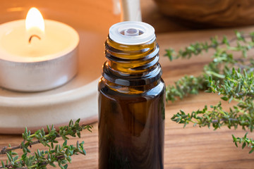 A dark bottle of thyme essential oil with fresh thyme twigs