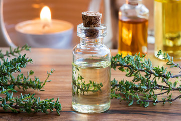 A transparent bottle of thyme essential oil with fresh thyme twigs - obrazy, fototapety, plakaty