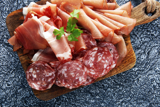 Food tray with delicious salami, pieces of sliced ham, . Meat platter with selection.