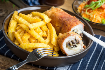 Fried chicken breast stuffed with mushrooms and cheese wrapped in ham served with fries and salad.