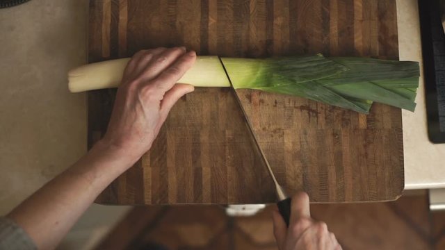 Woman cuts a leek into two halves of a video