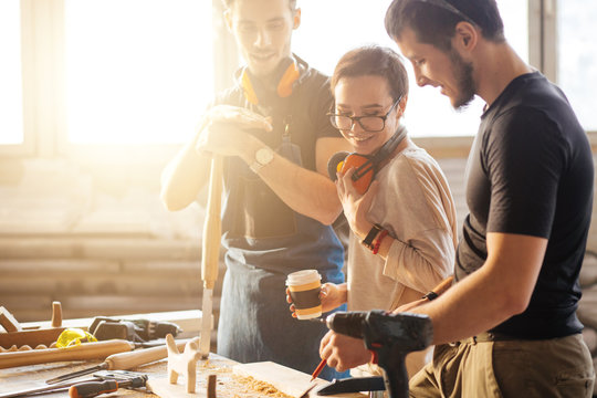 Carpenter showing apprentice how to use sawing machine