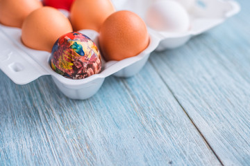 Fototapeta na wymiar Сolorful easter eggs in eggs box with white and brown