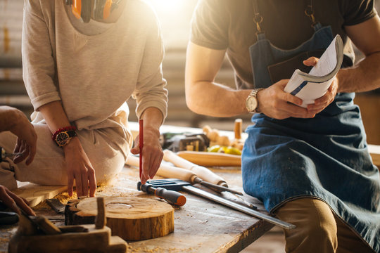 Carpenter showing apprentice how to use sawing machine