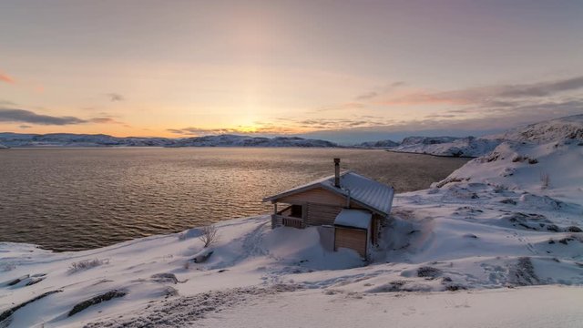 Cottage on the shore of the Arctic Ocean at dawn in winter