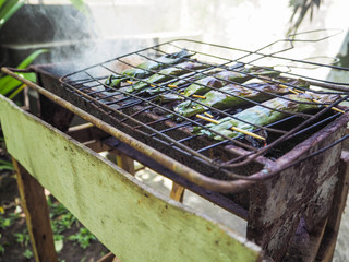 Fish in banana leaves ( called Pepes Ikan) grilling on a bbq, Ubud, Bali
