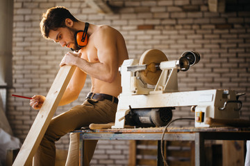 naked carpenter using straightedge to draw line on board.