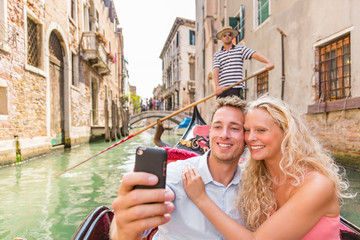 Obraz premium Para bierze selfie w Wenecja gondoli romantycznej łódkowatej przejażdżce szczęśliwi turyści na miesiąca miodowego podróży wakacje wakacjach. Młodzi ludzie żeglują w weneckim kanale w gondoli. Włochy. Święto Europy.