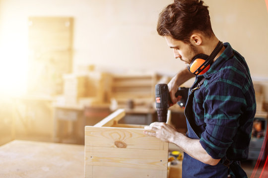 Carpenter drills a hole with an electrical drill