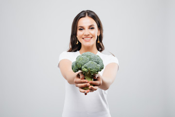 Portrait of a beautiful smiling woman with broccoli, isolated on white background