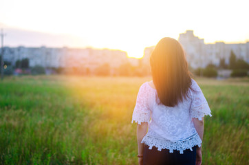 Young woman admires the sunset  back view.  outdoor. summer. view of the city. life style