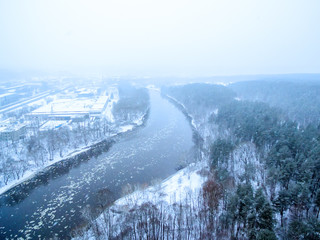 It is snowing in Vilnius, Lithuania, aerial top view of Neris river in winter