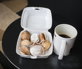 Scene depicting a container with walnut cookies and  a coffee mug.
