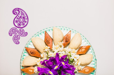 Novruz celebration plate with traditional national pastries in Azerbaijan shekerbura and pakhlava decorated with spring  flowers daffodils and purple fleur de lis silk light grey background copy space