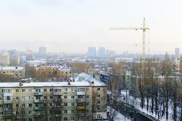 View of apartment houses from the top. Construction crane. Winter time.