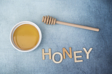 Pot of sweet honey with honey drizzle and the word honey on a blue background 