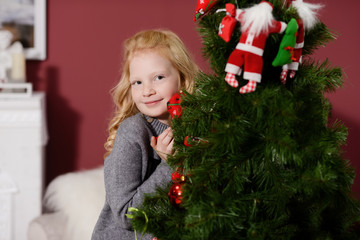 the girl in the next to the white fireplace, decorate a Christmas tree with toys