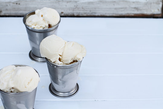 Frosty metal cups filled with scoops of creamy vanilla ice cream.