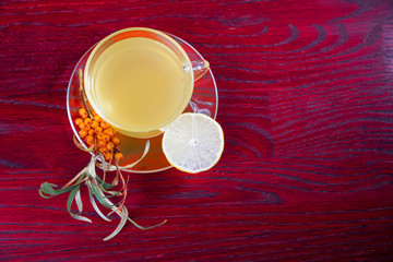 Tea made from sea buckthorn berries healthy for health delicious, saturated with vitamins surrounded by berries and sea buckthorn leaves and maintaining health in the body top view