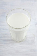 Fresh milk in a glass on white kitchen wood plate can be used as background