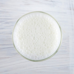 Fresh milk in a glass on white kitchen wood plate can be used as background