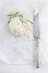 fresh cream cheese with knife and oregano on white paper and white wood table can be used as...