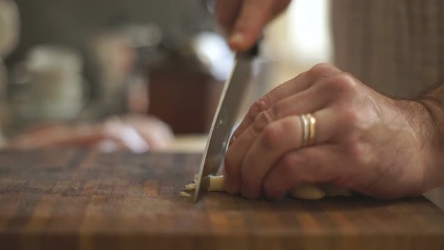 Man is cutting garlic on a wooden board