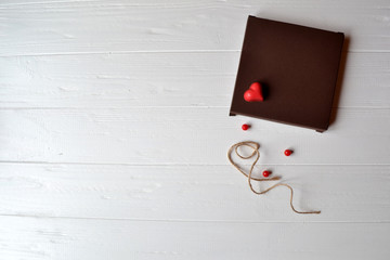 Candle, red hearts, rope and gift box on the white wooden desk. Valentine's Day. Background with place for text.